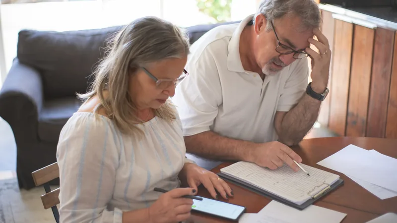 Couple de retraités examinant des documents financiers